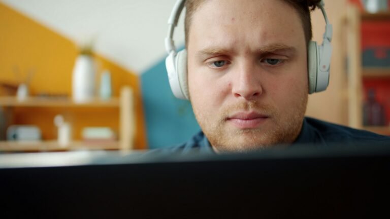 Joven con audífonos frente a la pantalla de su computadora