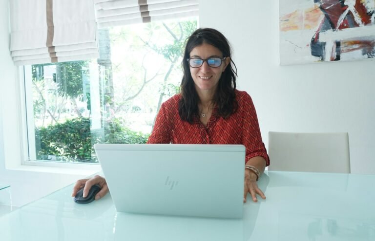 Mujer sonriendo mientras trabaja en su laptop en casa